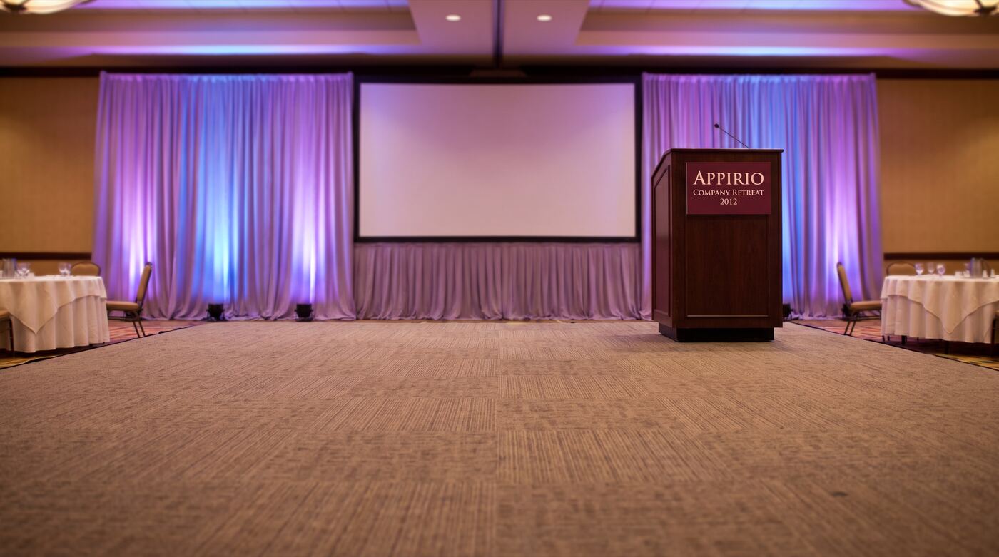 A hotel ballroom stage with a podium sign for the 2012 company retreat